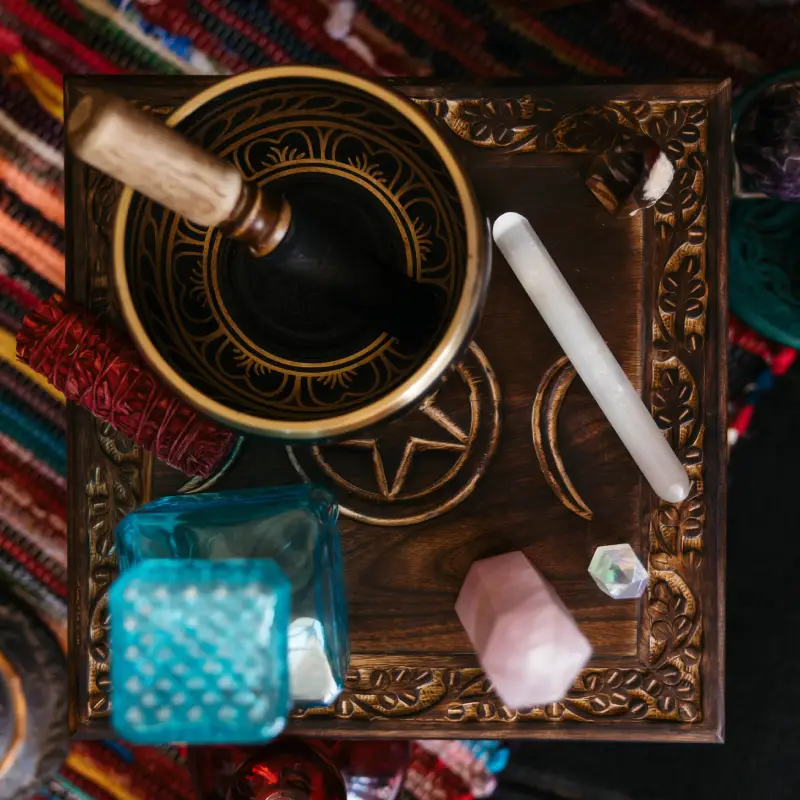 An overhead view of a wooden altar with a mortar and pestle, colorful crystals, and a mystical pentacle design.