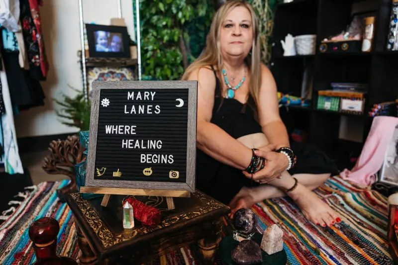 A tray displays colorful crystals and a business card for Mary Lane's Holistic Practice, alongside a small elephant figurine.