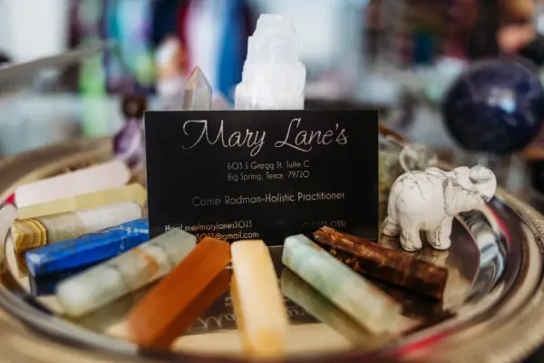 A tray displays colorful crystals and a business card for Mary Lane's Holistic Practice, alongside a small elephant figurine.